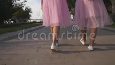 两条穿薄纱裙子的女士腿和户外行走的运动鞋