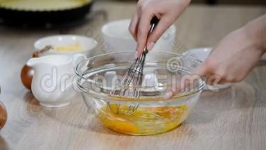 女厨师在厨房餐桌上用玻璃碗搅拌鸡蛋