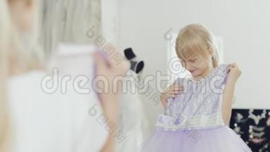 金发女孩6岁看着她的新优雅的裙子。 看到镜子里的倒影