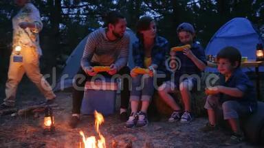 晚上在大自然的火焰附近用餐，全家人享用含盐的玉米，户外野餐，野营