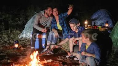 幸福家庭在森林篝火附近的手机上<strong>拍照</strong>，带着孩子的父母进入旅游营地<strong>拍照</strong>，