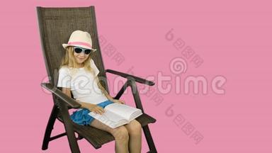 一个年轻的女孩坐在椅子上，笑着读一本书。