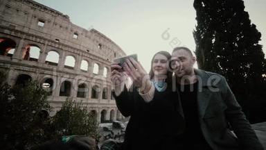 快乐的旅行情侣一起在意大利罗马斗兽场附近的智能手机上自拍，以获得回忆。