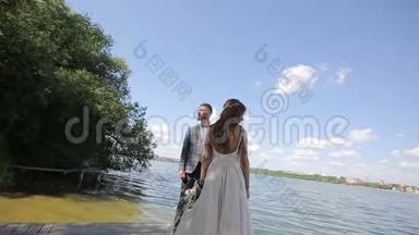 一对年轻漂亮的新婚夫妇站在湖边。 <strong>结婚纪念</strong>日。 慢动作
