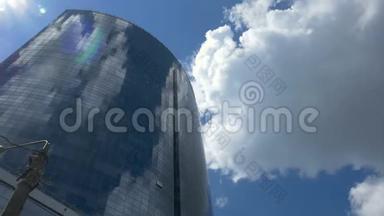 从下面的一个大玻璃商务中心，在，背景是移动的灰色云。 在玻璃里反射。