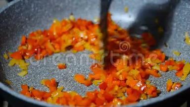 炒锅与切碎的洋葱和胡椒在热板上。