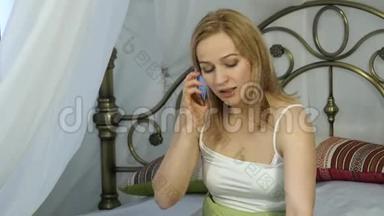 情绪化的美丽金发女人在床上打电话唱<strong>歌</strong>。 4K