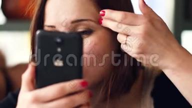 一个年轻女人用手机里的镜子，调整妆容
