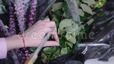 工作时花店的近景：一家花店里的妇女剪花包装玫瑰