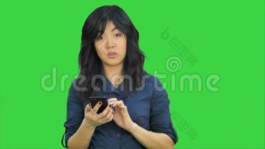 亚洲女商人在智能手机上阅读演示文稿，看绿色屏幕上的相机，Chroma键