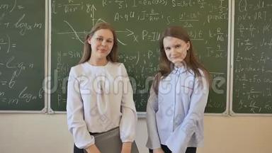 两个女学生在用<strong>数学公式</strong>画的学校董事会<strong>背景</strong>下摆姿势。