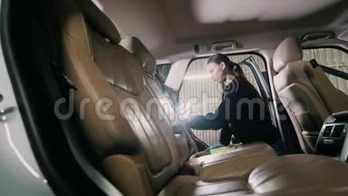 清洗车辆-白种人年轻女子正在清洗一辆豪华轿车的扶手椅