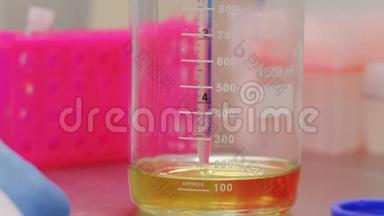 <strong>生物技术专家</strong>从玻璃瓶中取出一个黄色液体的样品进行测试