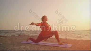 在海滩上日落时瑜伽。 做瑜伽，做体式的女人
