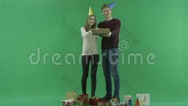 年轻夫妇把圣诞<strong>礼品</strong>盒<strong>展</strong>示给相机，彩色钥匙在背景上