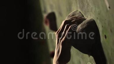 一个登山者的特写在室内的石墙上爬。 雕塑。 手固定在终点.. 练习是