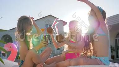 穿着泳衣的小女孩在别墅附近的背光区玩得很<strong>开心</strong>，有<strong>钱</strong>的孩子在日光浴床上，手里拿着椰子鸡尾酒在户外