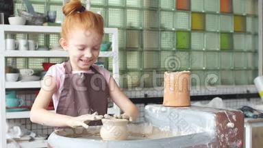 快乐的孩子正把一个陶土花瓶压在车轮上，孩子正慢慢地在陶轮上工作，然后把一个花瓶塑成一个金色的小花瓶