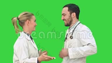 快乐的年轻医生穿着白色医疗<strong>整体</strong>舞蹈在绿色屏幕，Chroma键。