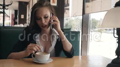 年轻漂亮的现代女人和一个女朋友通电话。 一个女孩正在咖啡馆里休息，在打电话。