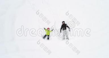 头顶俯视着母亲和孩子女儿躺在白色覆盖的冬天雪场上做雪天使。 妈妈
