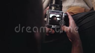 人的特写镜头打开一个旧的移动胶片相机的录像机封面。 摄影师拍年轻女人的照片。