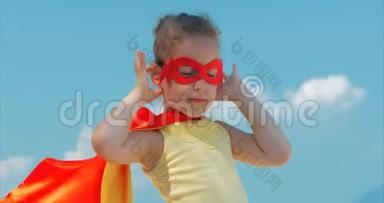 穿着超级英雄服装的漂亮小女孩，穿着红色斗篷和英雄的面具。 背景图