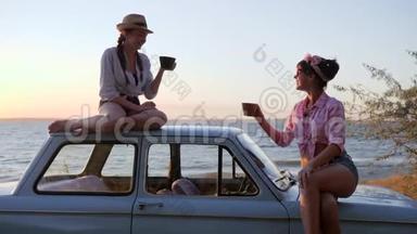 在日落的时候，女孩们手里拿着杯子在海边开车，在日落的时候，朋友们的<strong>茶会</strong>在海岸上机器，