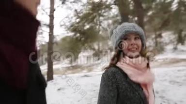 户外冬季拍摄，年轻的新婚夫妇在雪天松林中奔跑，玩得开心