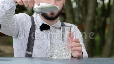 上班的酒吧老板把冰块放进玻璃特写镜头，酒吧柜台的酒吧老板把冰块放进玻璃里放酒精，