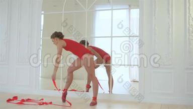 年轻漂亮的芭蕾舞演员穿着红色的衣服，红色的身体，红色的尖鞋，带着红色的丝带，一辆芭蕾舞火车，带着红色的丝带。