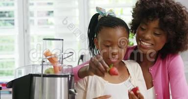 妈妈和女儿把草莓放进榨汁机里
