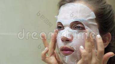 关闭年轻女人做面膜。 年轻的女人做一个美容面膜护肤。 护肤用化妆品面膜..