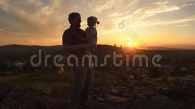 一个幸福的家庭在日落时，父亲正把女儿抱在怀里。
