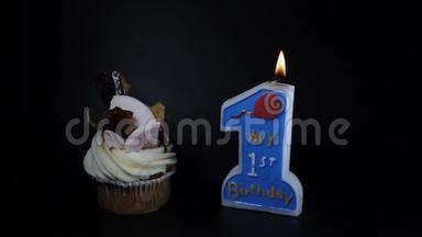 生日会盛宴庆祝理念.. 一个蛋糕和一支黑色蜡烛。 <strong>一周年</strong>纪念日。 点燃蜡烛