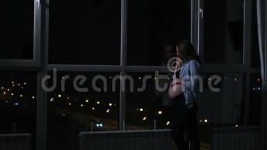 一位孕妇在晚上用手机说话，双手举着大全景，摸着肚子