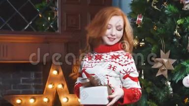 快乐的红发女孩穿着红色毛衣，拿着圣诞礼物，微笑着。