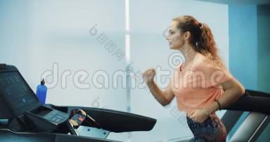 漂亮的卷发女孩在运动健身房的跑步机上跑步