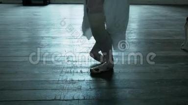 有木地板的尖角舞者。 芭蕾舞演员穿着尖角鞋，穿着一件<strong>白色</strong>连衣裙，腿上绑着绷带。 芭蕾舞演员