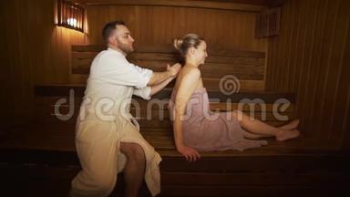 男人在桑拿、沐浴中做背部和颈部按摩美女。