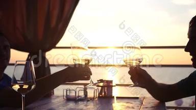 日落时分，两个朋友坐在海边，手里拿着一杯<strong>酒</strong>。 高清，1920x1080。 慢动作