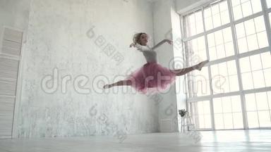 优雅的女孩在工作室练习芭蕾。 美丽的芭蕾舞演员表演跳跃和古典芭蕾