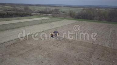 一名农民在一辆拖拉机上，带着播种机在村庄地区的一个私人田地里播种谷物。 弹簧场的机械化