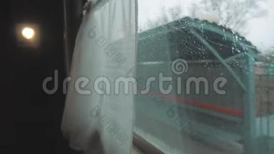 火车从火车站出发。 从火车窗口的视图，车窗上的雨。 人口