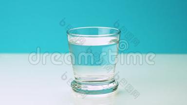 一粒止痛的泡腾药丸<strong>落入</strong>玻璃杯中，将慢镜头的阿司匹林溶解在一片水蓝色的水中