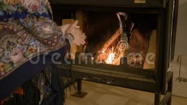 家庭舒适。 女人在火边暖手。 冬天很暖和。