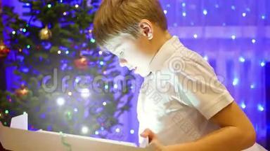 圣诞礼物惊喜-一个孩子惊奇地打开一份圣诞礼物。 发光的灯光从礼品盒中飞出