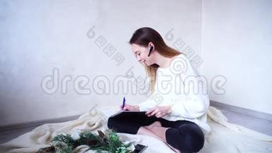 成功的女摄影师在蓝牙耳机上<strong>安排会议</strong>，在家工作，坐在格子布上的地板上。
