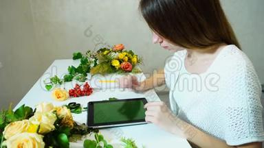 妩媚的花艺师在编花的时候，与pla坐在同一桌，看着平板电脑的流行趋势