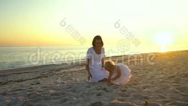 日落时分，年轻漂亮的女人和她的小女儿在海滨散步。 他们很开心。 剪影贴在